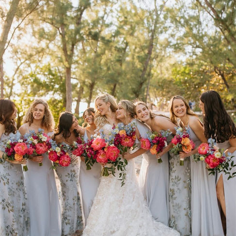 Bridesmaids smiling at each other in outdoor group photo with bride
