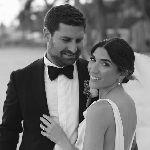 Close-up of groom gazing at bride while she looks confidently at camera