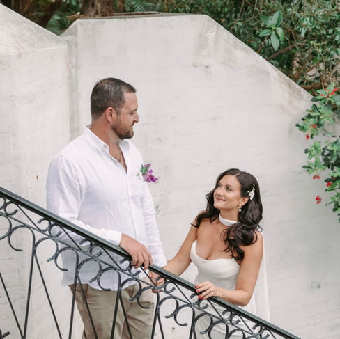 Bride and groom standing on staircase, sharing a romantic glance