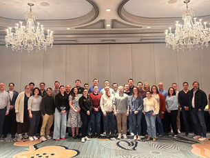 A group of Land & Liberty individuals gathering for a group photo in a ballroom