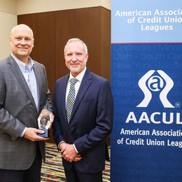 man in tie accepting award for another man