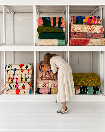 Une femme en train de ranger des tapis berbères colorés