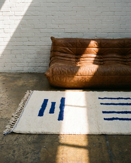 Una alfombra bereber minimalista en un taller de estilo industrial frente a un sofá Togo