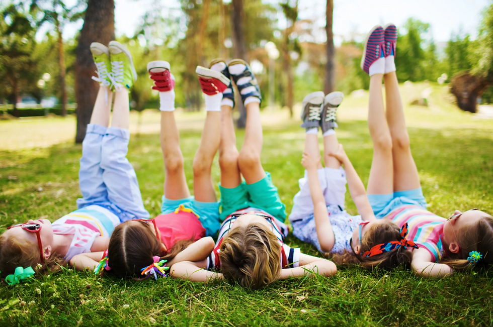 Crianças de férias com as pernas pro ar em um jardim. Post sobre férias educativas