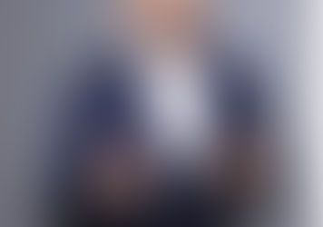 Businessman smiling and wearing a suit, portrayed in a professional setting. The image reflects confidence, experience, and approachability — suitable for an article on leadership and transition