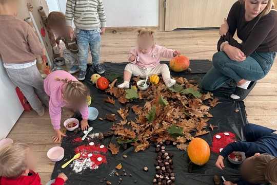 Jesienne zabawy sensoryczne w MegaMocnych – dzieci z opiekunką bawią się kasztanami, liśćmi, dyniami i kolorowym ryżem ułożonym w drzewo i muchomory