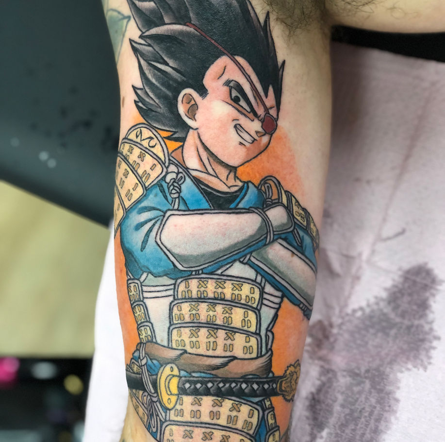 anime tattoo on the inner bicep in colour of vegeta from the anime series dragonball z done in a japanese influenced style where he's wearing samurai armour instead of his usual armour 