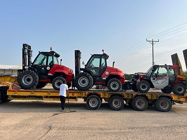 שלוש מלגזות טלסקופיות אדומות מועמסות על נגרר שטוח להובלה.