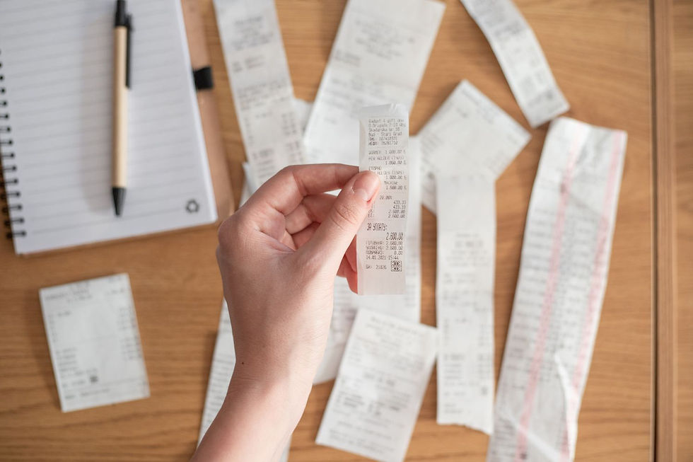 Hand holding a receipt over a bunch of receipts