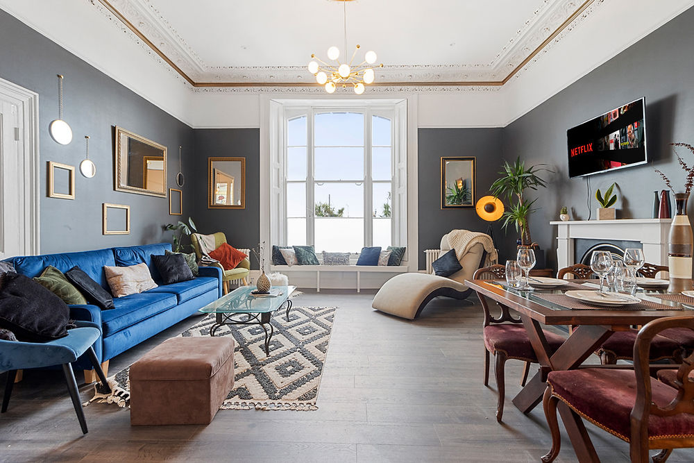Modern living room with blue sofa, dining table, and large window