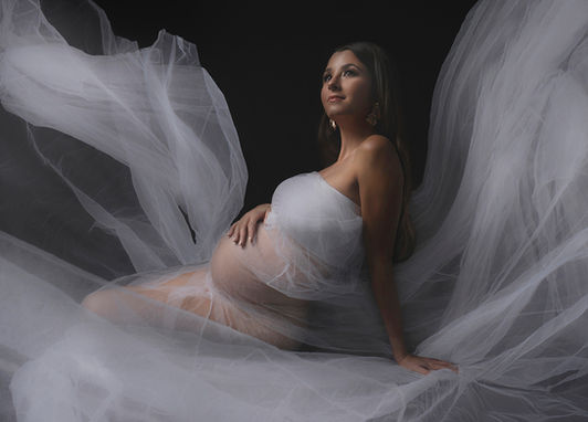 Fine art maternity portrait in studio – pregnant woman posed gracefully under dramatic light, highlighting natural beauty and timeless elegance by Drea Lugo Photo