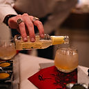 dettaglio della mano di un barman che versa un drink in un bicchiere