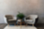 Two cozy grey armchairs standing on white carpet in empty room.jpg