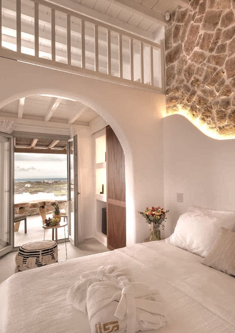 A superior suite with exposed brick feature walls, concealed lighting and views of the Aegean.