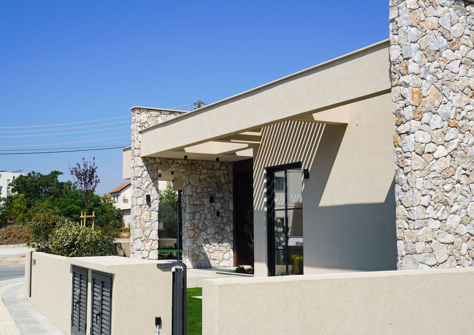Villa Gaia street elevation with stone-clad columns, a projecting roof and slatted shading above the front windows.