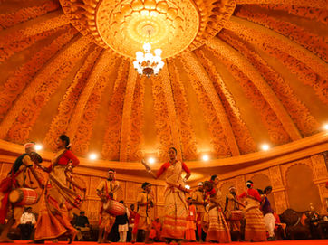 Kumbh Mela Dancing performers in traditional dress under a decorative domed ceiling.