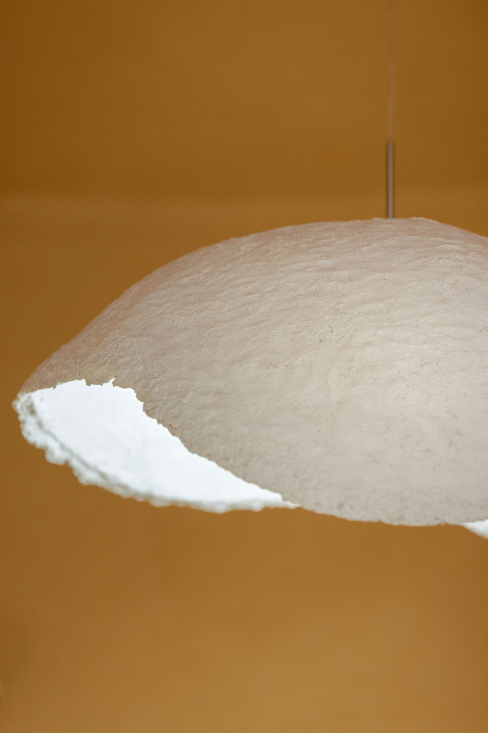 White, textured pendant light with a unique design, hanging from ceiling.