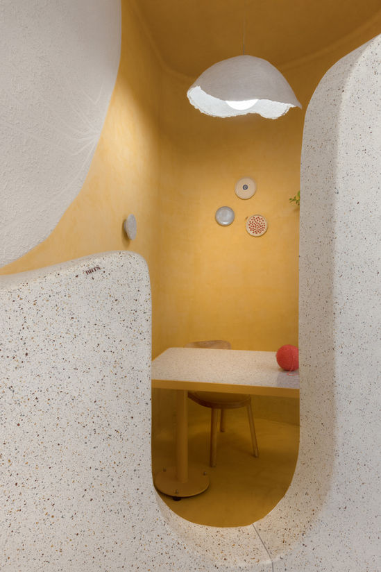 Cozy yellow cafe with small table and decorative plates on the wall.
