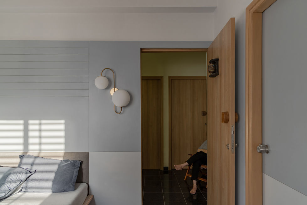 Modern wall lamp on blue and white wall, open door, person seated inside.