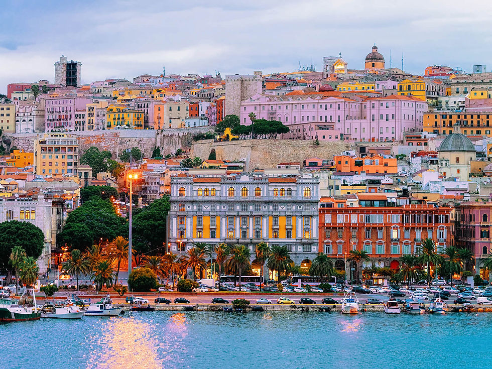 Colorful seaside cityscape at dusk with pastel buildings, illuminated windows, palm trees, and boats on calm water, under a cloudy sky.