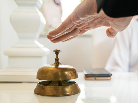 Header image of a person's hand about to hit a hotel's service bell, related to the blog post: Unlock travel brand growth: Mastering SEO, content and online engagement for tangible results