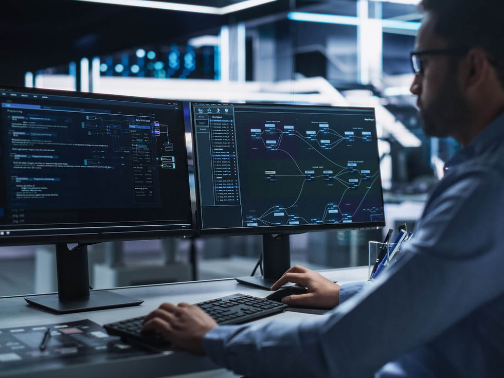 Persona en oficina frente a dos monitores con gráficos y código. Ambiente tecnológico y moderno. Luces azules de fondo.