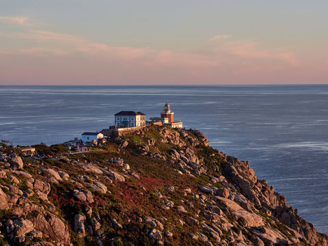 Header image of a lighthouse on a rocky cliff at sunset related to the blog post: "Is this Spain's most dramatic coastline? The ultimate road trip along the Coast of Death."