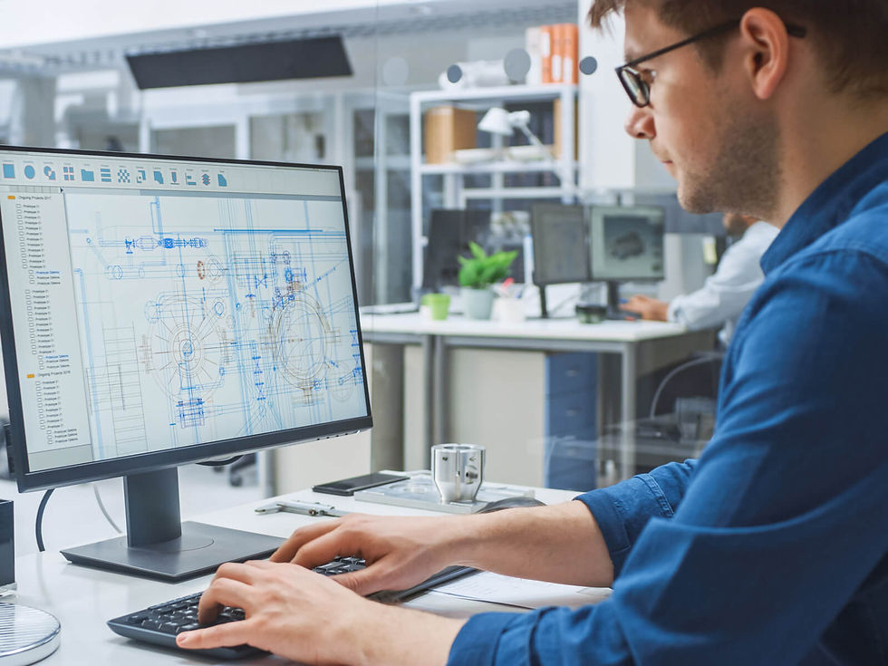 Hombre en oficina moderna, con camisa azul, trabaja en computadora con planos técnicos en pantalla. Ambiente profesional y enfocado.