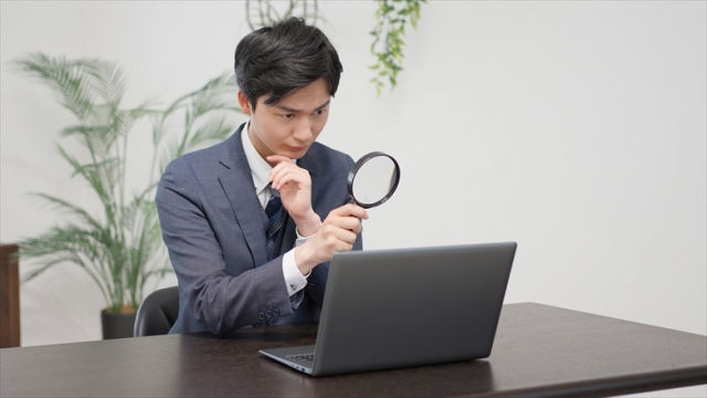 虫眼鏡で確認する男性
