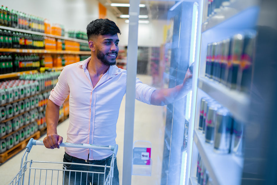 A Latin American man with a shopping cart takes frozen food from the supermarket refrigera