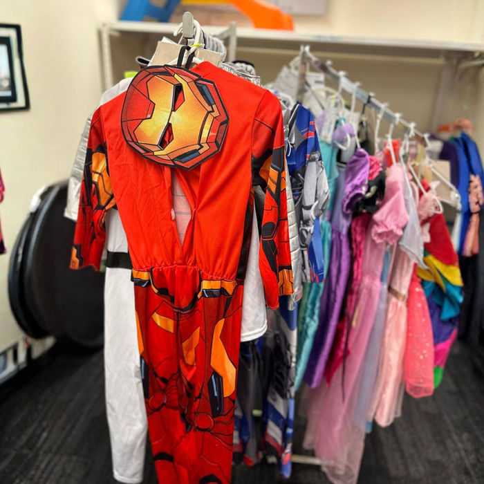 Rack of children's dress-up costumes available to borrow from a toy library.