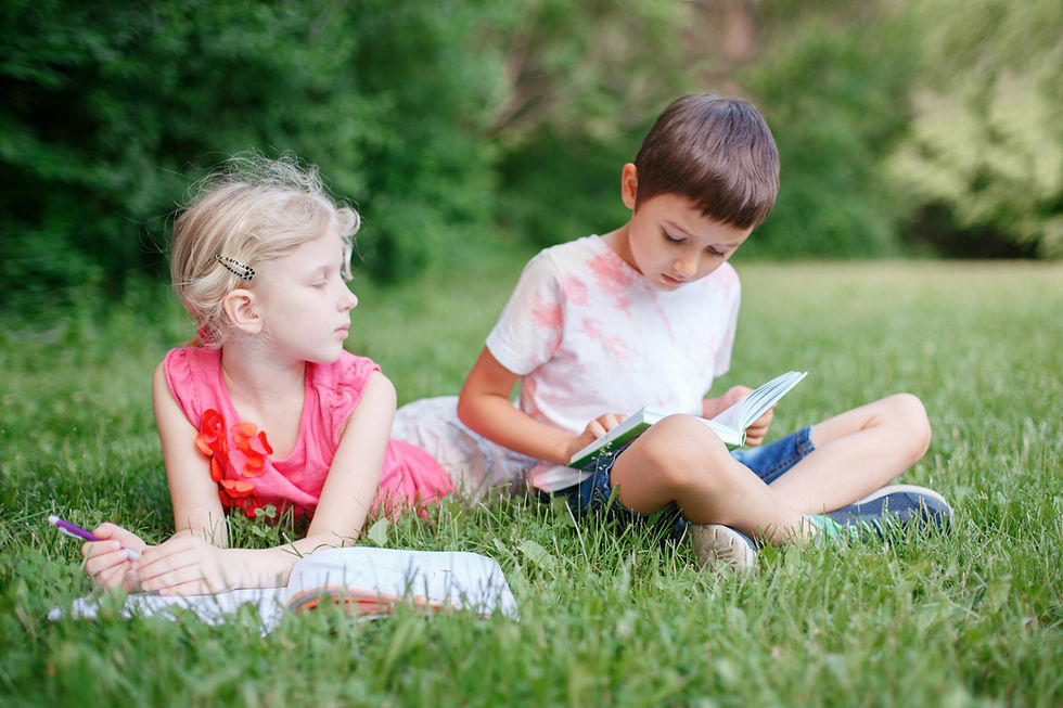 A young boy and little girl reading books sitting in the grass demonstrate not all are children who can't read.