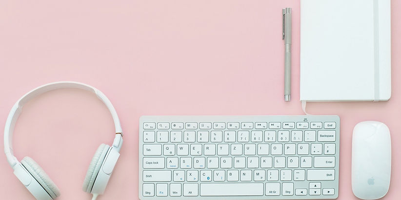 White headphones, keyboard, mouse, notebook, and pen