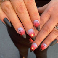Almond-shaped nails with red and black gradient sunset design and silhouetted floral details – luxury nail art at Nailed It of Naples.