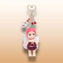 Cute doll keychain from Gifty Pleasure Store, featuring a fairy-like character with wings, a pink fruit cap, red skirt, and decorative charms including a heart and cherries.