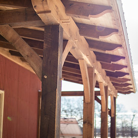 A timber frame porch addition on a large barn.
