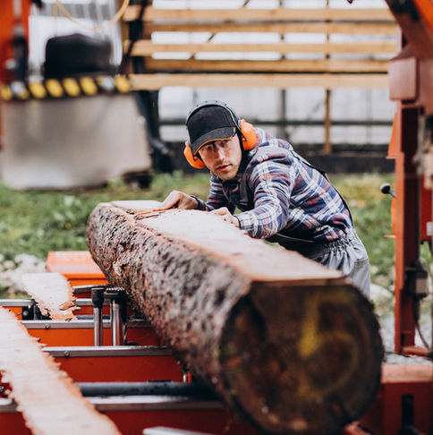 A man cutting a log on an orange sawmill.
