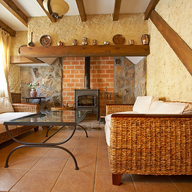 A small living room with furniture, a wood burning stove, and wood beam accents.