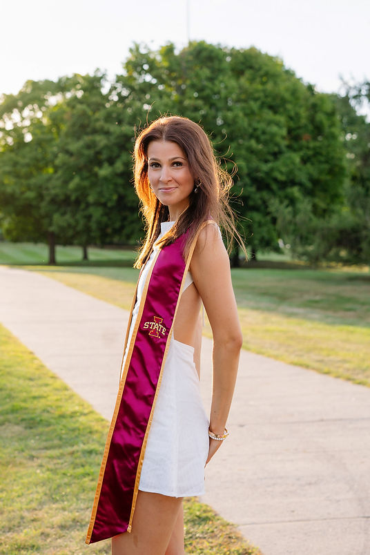 Iowa state graduate wearing stole standing in front of Beardshear on campus in Ames