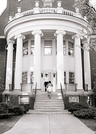 Boyfriend watching girlfriend walk up stairs wearing graduation caps on Iowa State campus