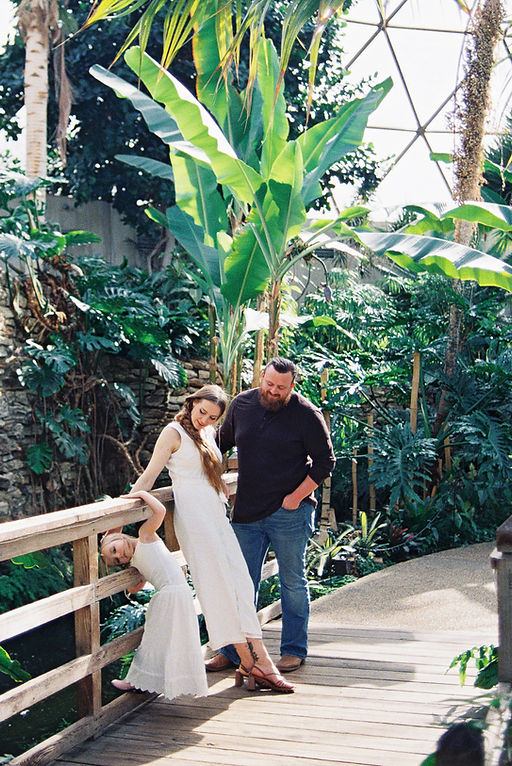 Parents and a toddler girl standing near a wooden railing at the Des Moines Botanical Garden