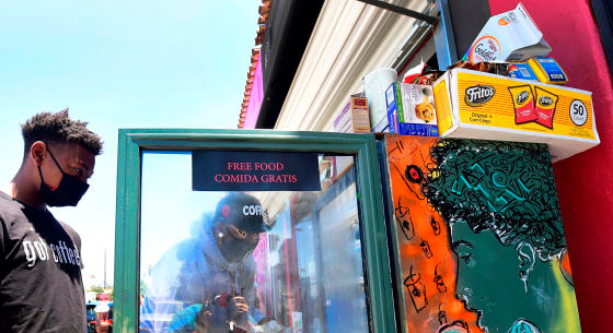 Solo Morris holds the fridge door open as Danny Dierich stocks it with more items outside the Little Amsterdam Coffee shop in Los Angeles on July 16, 2020.