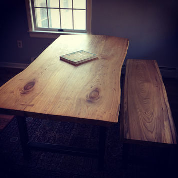 Live edge wood dining table and matching bench by a window