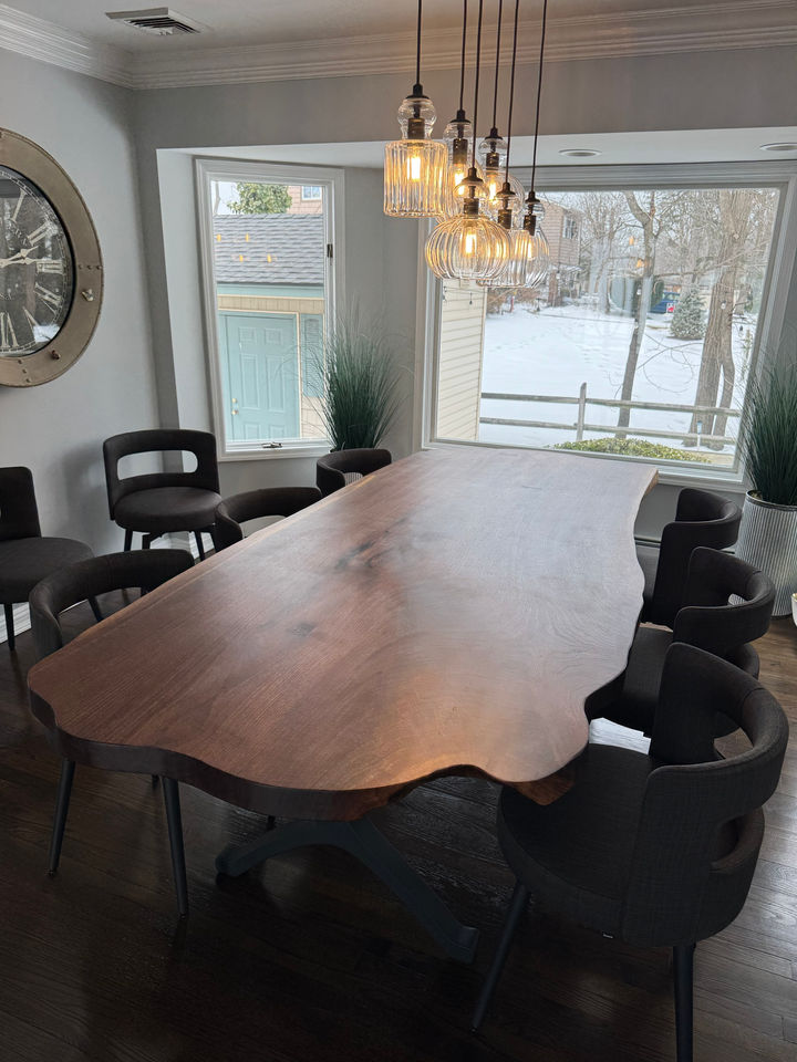 Live edge black walnut dining table under glass pendant lights, with snow outside the windows, Bayville, NY