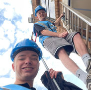 HG assist worker on ladder cleaning second storey window