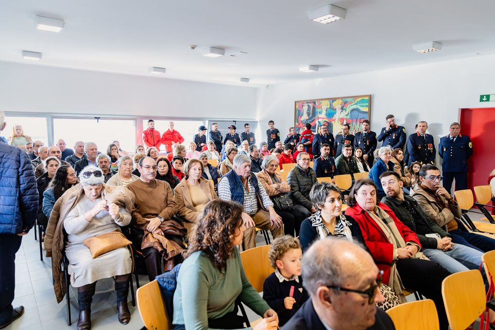 pessoas sentadas e de pé numa cerimónia numa sala