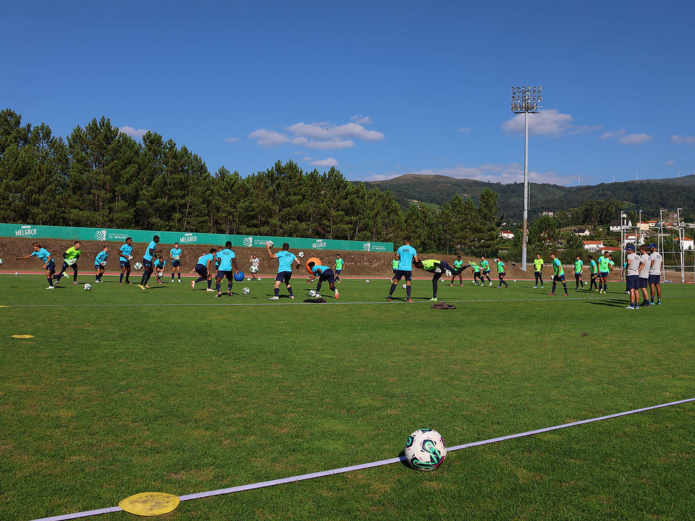 atletas jogando futebol ao ar livre, num complexo centro de treinos