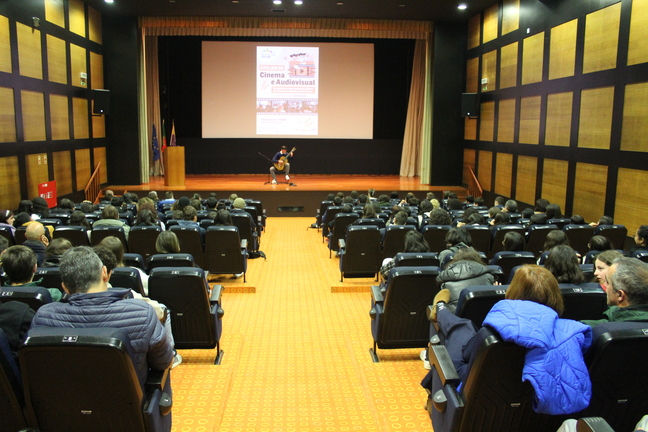 músico tocando viola num palco para um auditório
