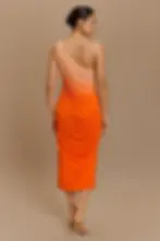 Woman wearing one-shoulder orange dress, back view with neutral background.