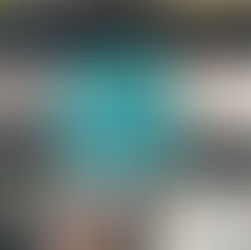 A hand holds a book titled "The Drummond Affair" against a bookshelf. The cover is teal with a vintage photo. Books are blurred in the background.